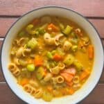 Bowl of coconut curry soup with vegetables and edamame. Soup is topped with red chili flakes.