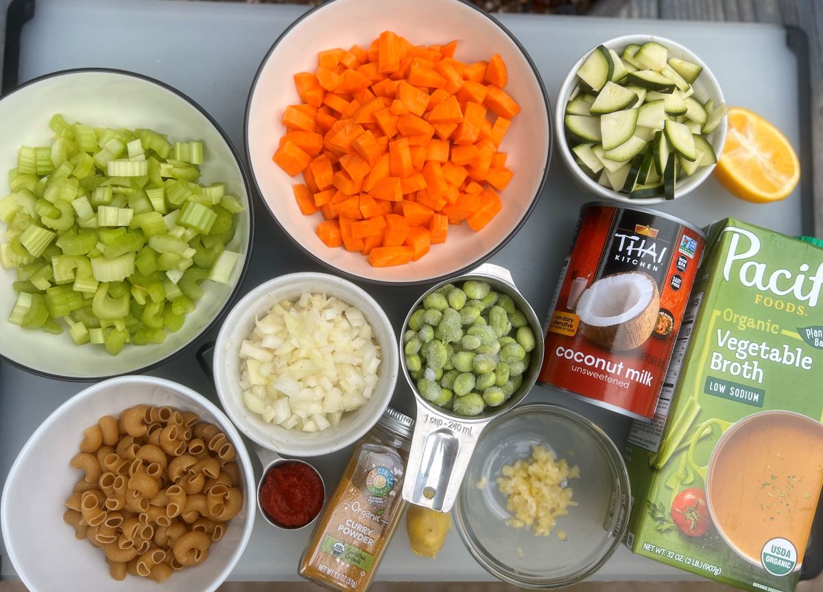 Photo of all the ingredients in the soup. Veggies, lemon, coconut milk, low sodium veggie broth, curry powder, tomato paste, ginger, garlic, edamame, and noodles.