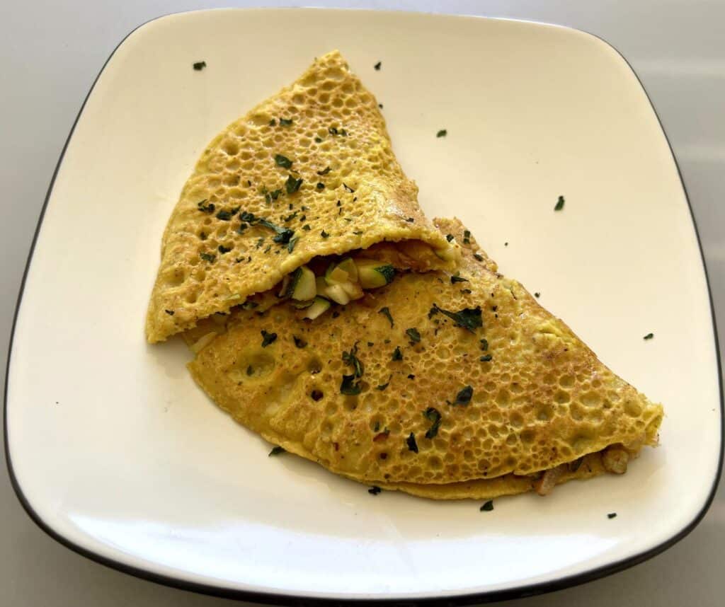 Eggless veggie omelette made out of chickpea flour with sauteed veggies inside.