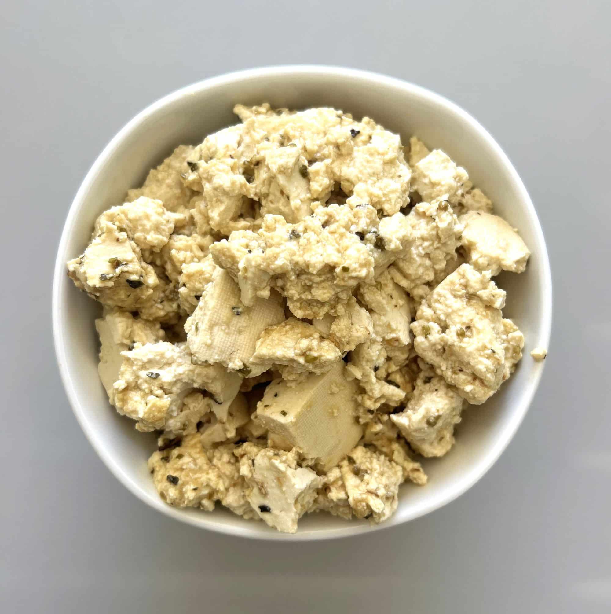 Bowl of plant based feta cheese made out of tofu and marinade.