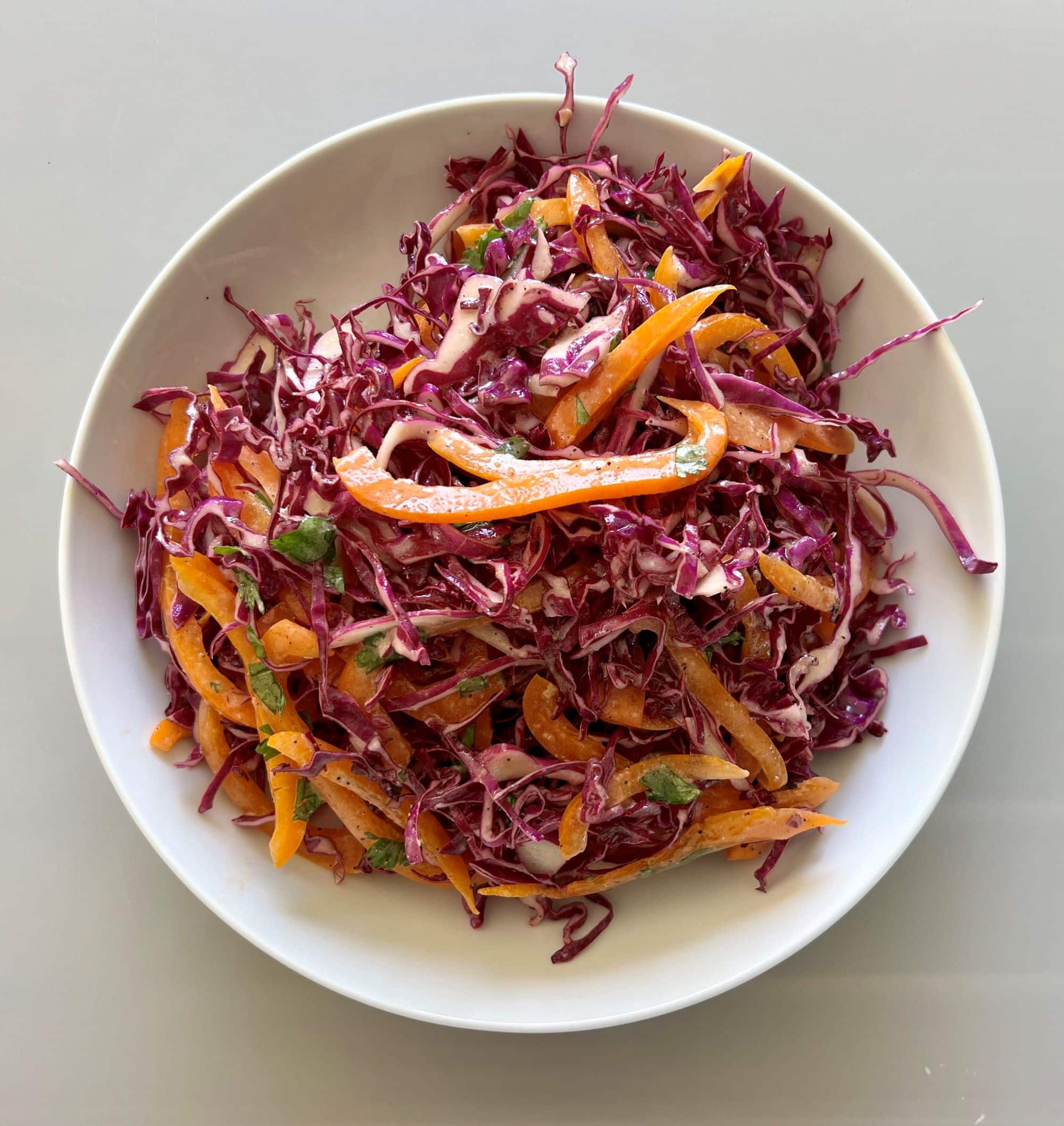 Purple cabbage slaw made out of cabbage, bell pepper, cilantro and dressing.