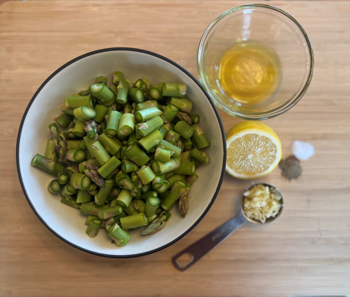 Ingredients to make Garlic Lemon Asparagus. Photo includes chopped asparagus, minced garlic, olive oil, lemon juice, salt and pepper.