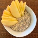 Bowl of overnight apple cinnamon oatmeal with sliced apples on top.