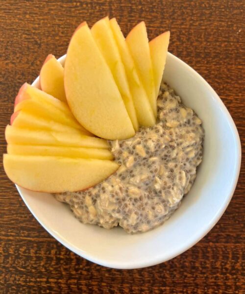 Bowl of overnight apple cinnamon oatmeal with sliced apples on top.