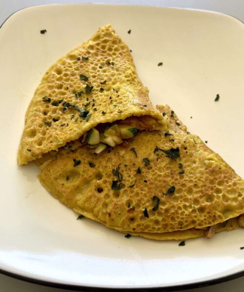 Eggless veggie omelette made out of chickpea flour with sauteed veggies inside.