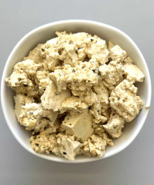 Bowl of plant based feta cheese made out of tofu and marinade.