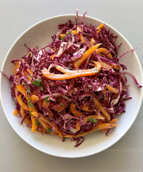 Purple cabbage slaw made out of cabbage, bell pepper, cilantro and a tangy dressing.