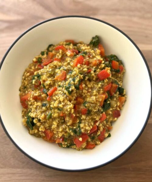 Bowl of savory vegetable oats with bell pepper, leafy greens, onion and seasonings.